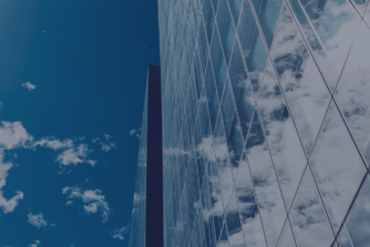 Modern glass office building under a blue sky representing efficiency and business growth through payroll outsourcing in Europe.